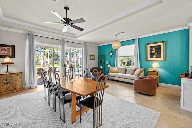 dining space with crown molding, ceiling fan, a tray ceiling, and light tile patterned floors