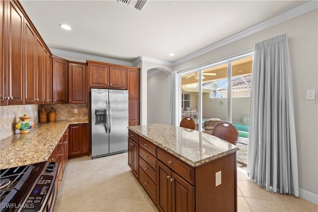 kitchen with crown molding, stainless steel appliances, a center island, light stone counters, and tasteful backsplash