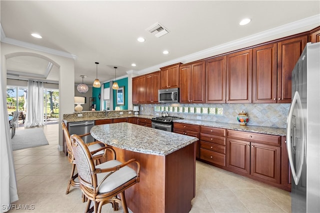 kitchen with appliances with stainless steel finishes, pendant lighting, a breakfast bar area, ornamental molding, and kitchen peninsula