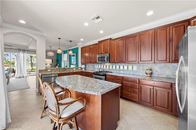 19550 Casa Bendita Ct, Estero, FL 33967 - kitchen featuring appliances with stainless steel finishes, arched walkways, ornamental molding, a kitchen island, and a kitchen breakfast bar
