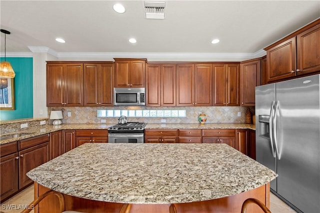 19550 Casa Bendita Ct, Estero, FL 33967 - kitchen with appliances with stainless steel finishes, a kitchen island, ornamental molding, light stone countertops, and decorative light fixtures