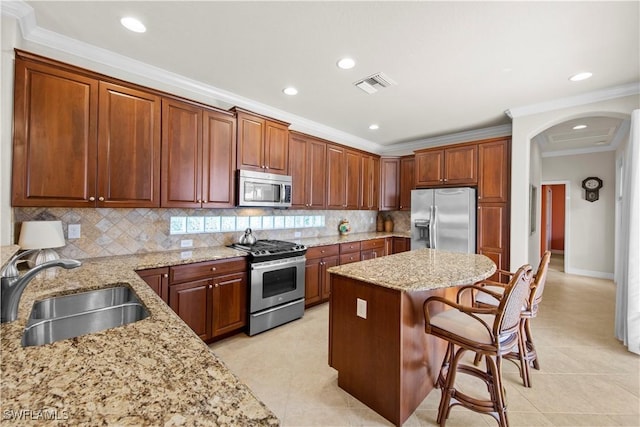 19550 Casa Bendita Ct, Estero, FL 33967 - kitchen with stainless steel appliances, a breakfast bar area, a center island, arched walkways, and light stone countertops