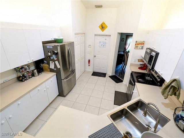 kitchen featuring stainless steel fridge, white cabinets, electric range, and light tile patterned floors