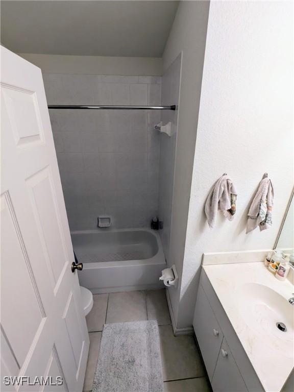 full bathroom with tile patterned flooring, vanity, tiled shower / bath combo, and toilet