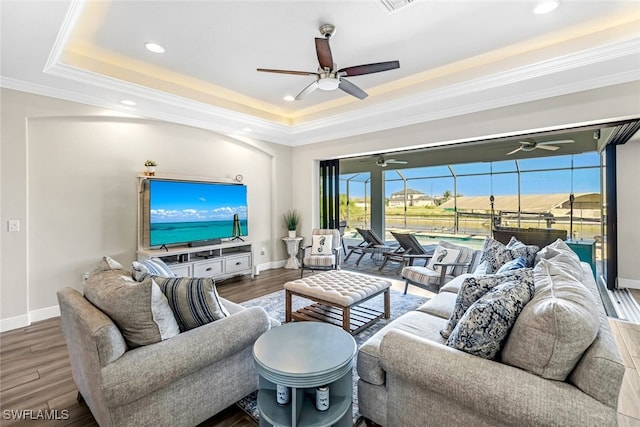 living room featuring a raised ceiling, crown molding, and hardwood / wood-style flooring