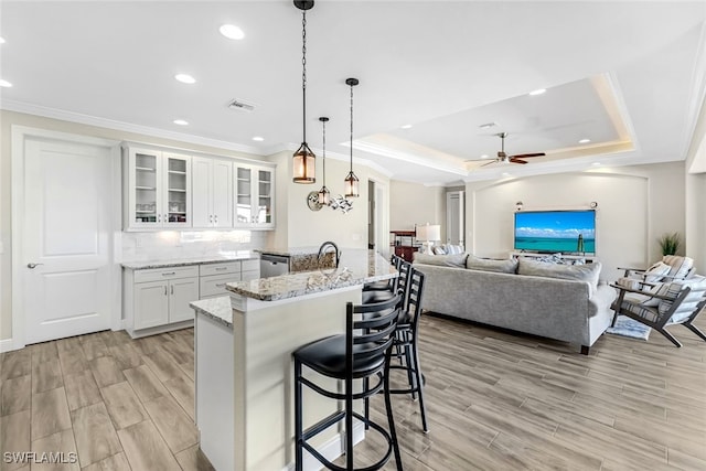 kitchen with a tray ceiling, white cabinetry, pendant lighting, and stainless steel dishwasher