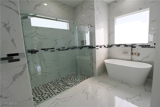 bathroom featuring shower with separate bathtub and tile walls