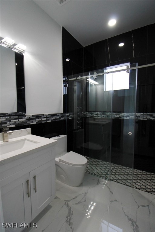 bathroom with vanity, a shower with door, toilet, and tile walls