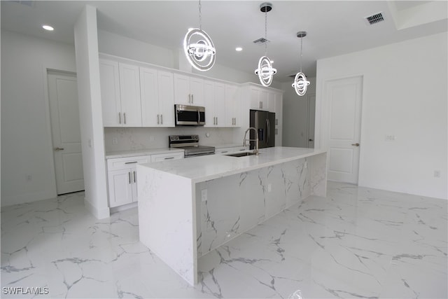 kitchen featuring white cabinets, stainless steel appliances, and an island with sink