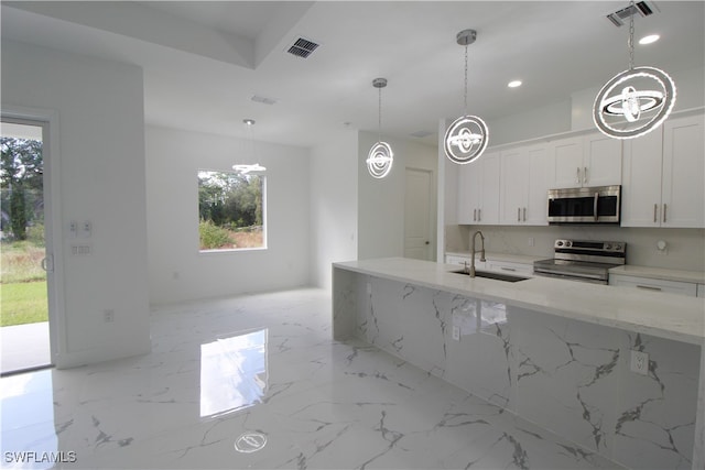 kitchen featuring appliances with stainless steel finishes, light stone counters, sink, pendant lighting, and white cabinets