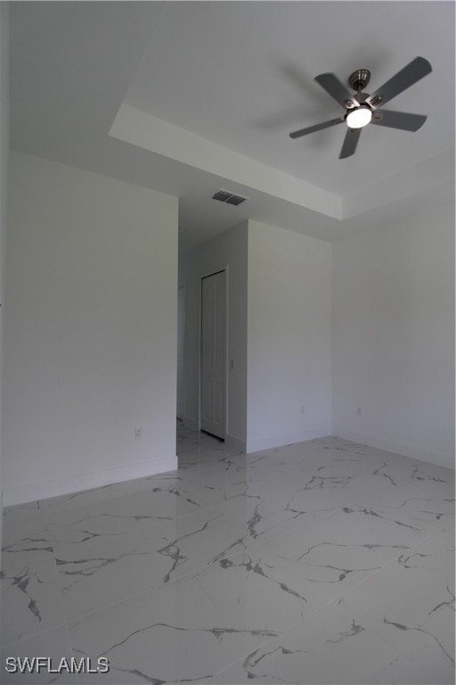 unfurnished room featuring a raised ceiling and ceiling fan