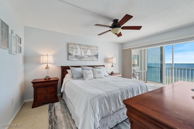 bedroom with access to exterior, a textured ceiling, light colored carpet, ceiling fan, and a water view