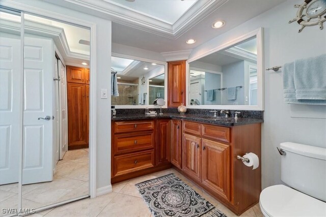 bathroom with tile patterned floors, vanity, a shower with door, crown molding, and toilet