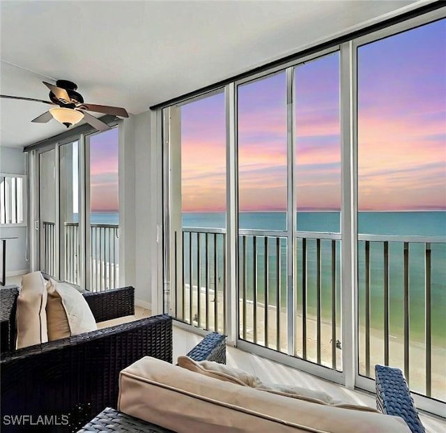 sunroom with a water view and ceiling fan