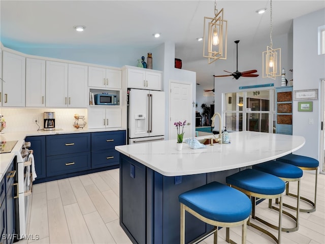 kitchen featuring pendant lighting, white appliances, a kitchen island with sink, ceiling fan, and white cabinetry