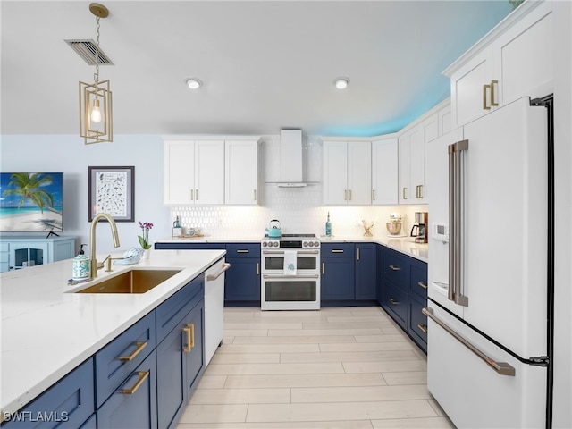 kitchen featuring white appliances, sink, wall chimney exhaust hood, blue cabinetry, and white cabinetry