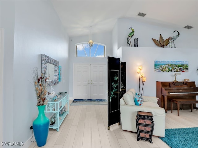 entrance foyer with hardwood / wood-style floors, an inviting chandelier, and high vaulted ceiling