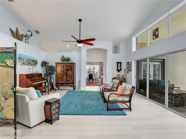 living room with ceiling fan, light hardwood / wood-style floors, and high vaulted ceiling