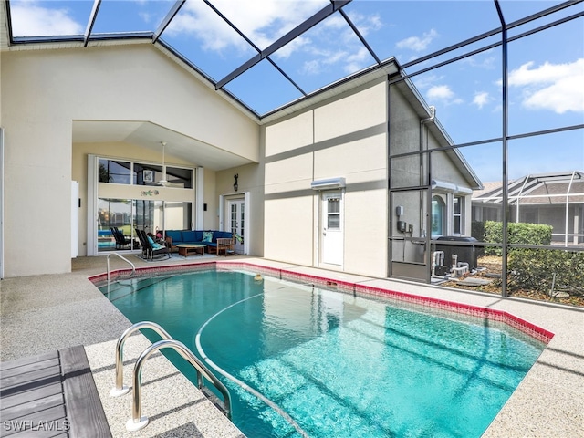 view of pool featuring glass enclosure, ceiling fan, a patio, and an outdoor living space