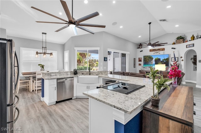 kitchen featuring sink, stainless steel appliances, pendant lighting, vaulted ceiling, and white cabinets