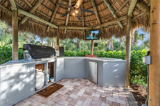 view of patio featuring a gazebo, ceiling fan, a grill, and exterior kitchen