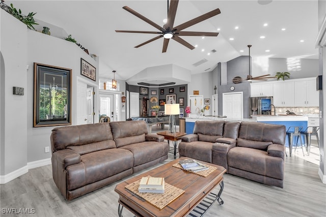 living room with light hardwood / wood-style floors, high vaulted ceiling, ceiling fan, and sink