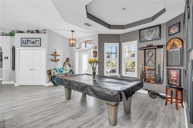 playroom featuring a raised ceiling, pool table, an inviting chandelier, and light wood-type flooring