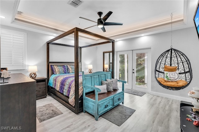 bedroom featuring ceiling fan, access to outside, a tray ceiling, and french doors