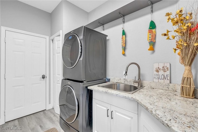 3930 24th Ave SE, Naples, FL 34117 - laundry area featuring stacked washer and clothes dryer, cabinet space, and light wood-style floors