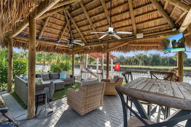 wooden terrace featuring outdoor lounge area, ceiling fan, a gazebo, a water view, and a patio