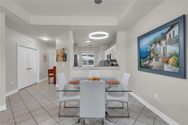 tiled dining room featuring a raised ceiling