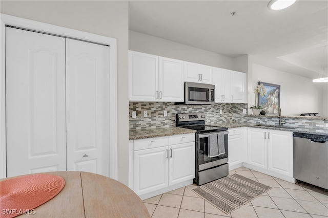 kitchen with decorative backsplash, white cabinetry, light stone counters, and appliances with stainless steel finishes