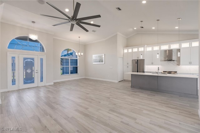 unfurnished living room featuring ceiling fan with notable chandelier, sink, light wood-type flooring, and crown molding