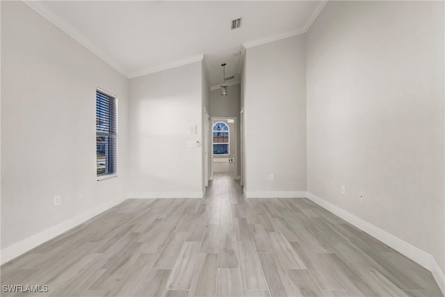 spare room featuring light hardwood / wood-style floors, vaulted ceiling, and crown molding