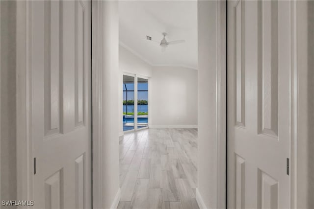 corridor with light wood-type flooring and crown molding