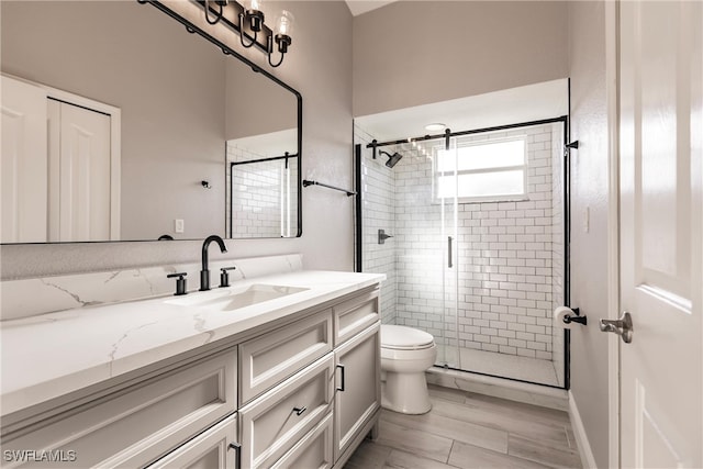 bathroom with hardwood / wood-style floors, vanity, toilet, and a shower with door