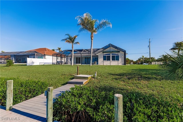 rear view of house featuring a lanai and a lawn