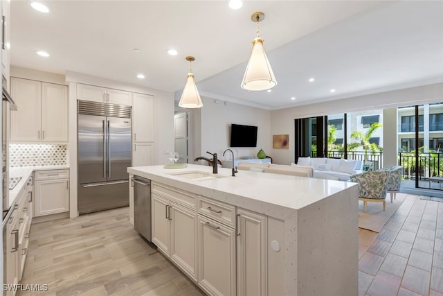 kitchen featuring pendant lighting, sink, white cabinets, a kitchen island with sink, and stainless steel appliances