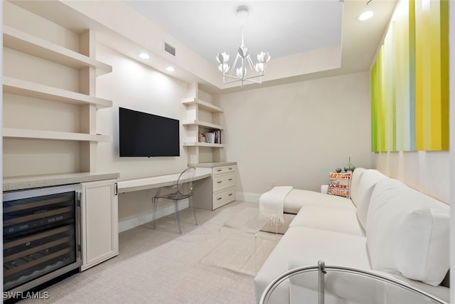 living room featuring built in desk, light carpet, a tray ceiling, a notable chandelier, and beverage cooler