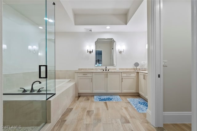 bathroom featuring vanity, plus walk in shower, hardwood / wood-style floors, and a tray ceiling