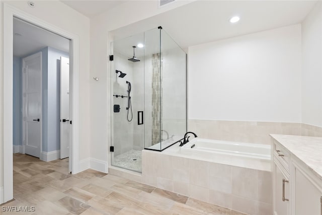 bathroom with vanity and shower with separate bathtub