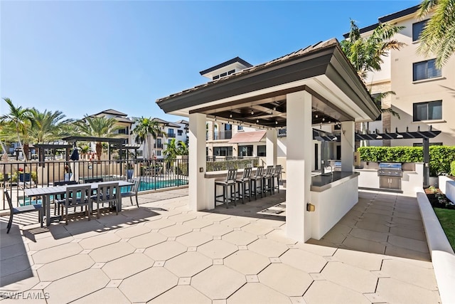 view of patio / terrace featuring a community pool, a pergola, a gazebo, exterior bar, and an outdoor kitchen