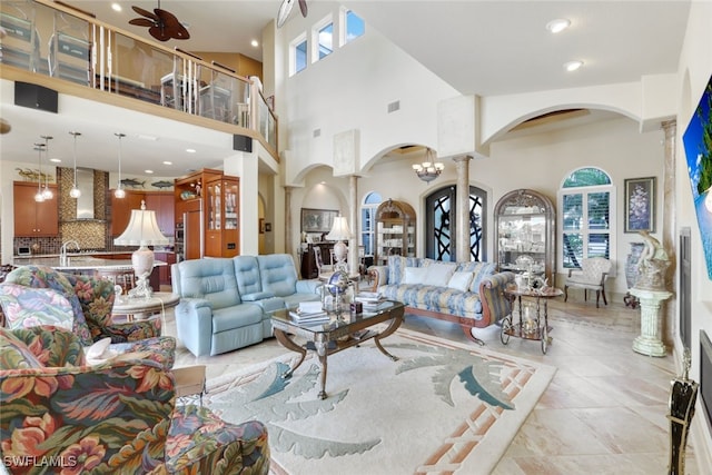 living room featuring a high ceiling, ceiling fan with notable chandelier, light tile patterned floors, and sink