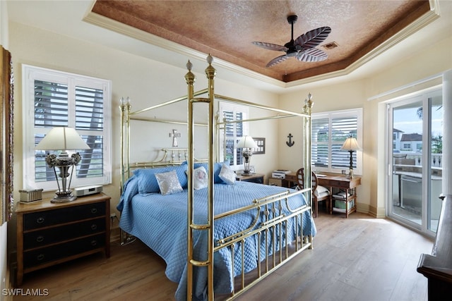 bedroom featuring hardwood / wood-style floors, ceiling fan, ornamental molding, a textured ceiling, and a tray ceiling