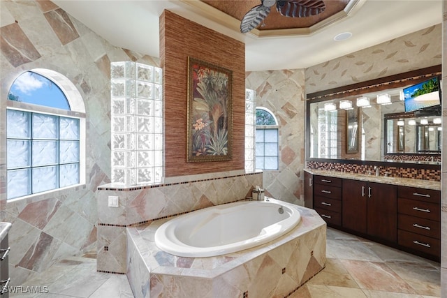 bathroom with tiled bath, vanity, and tile walls