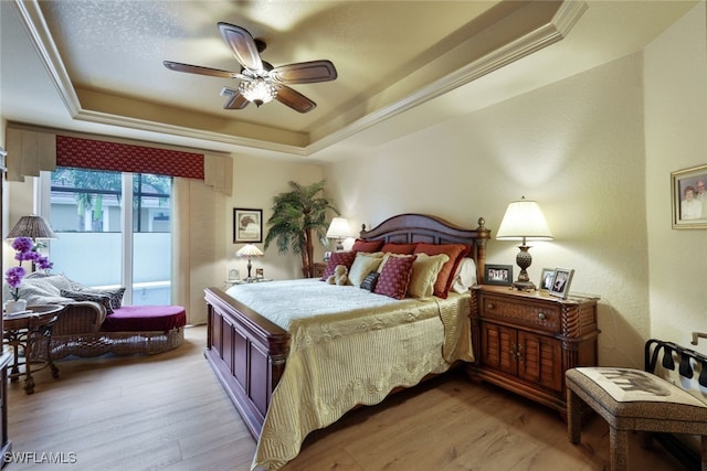 bedroom featuring a raised ceiling, ceiling fan, light hardwood / wood-style flooring, and ornamental molding