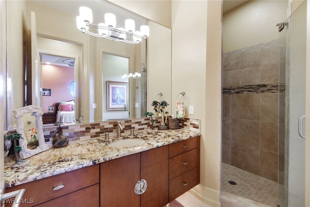 bathroom featuring backsplash, a shower with door, vanity, and an inviting chandelier