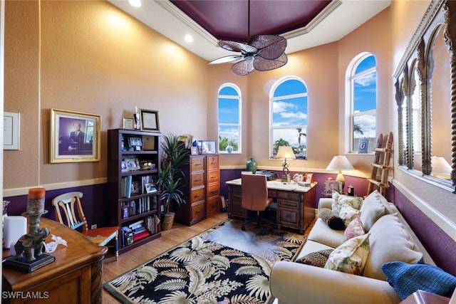 office space featuring a tray ceiling, light hardwood / wood-style flooring, plenty of natural light, and ceiling fan