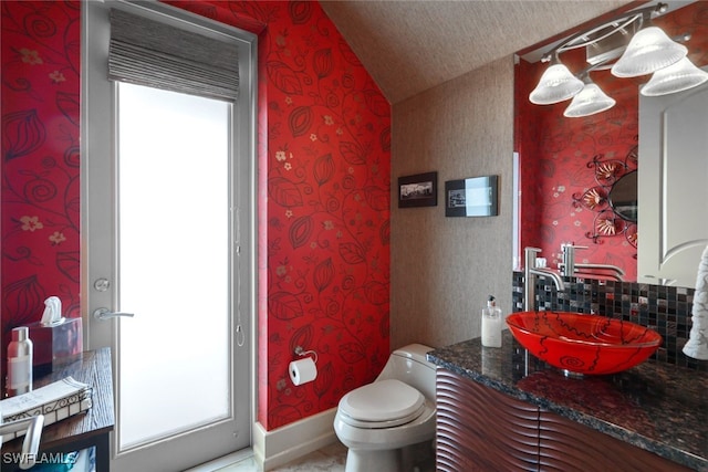 bathroom featuring a textured ceiling, a wealth of natural light, lofted ceiling, and toilet