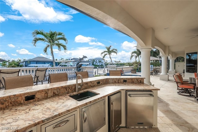 view of patio / terrace with area for grilling, ceiling fan, and an outdoor wet bar